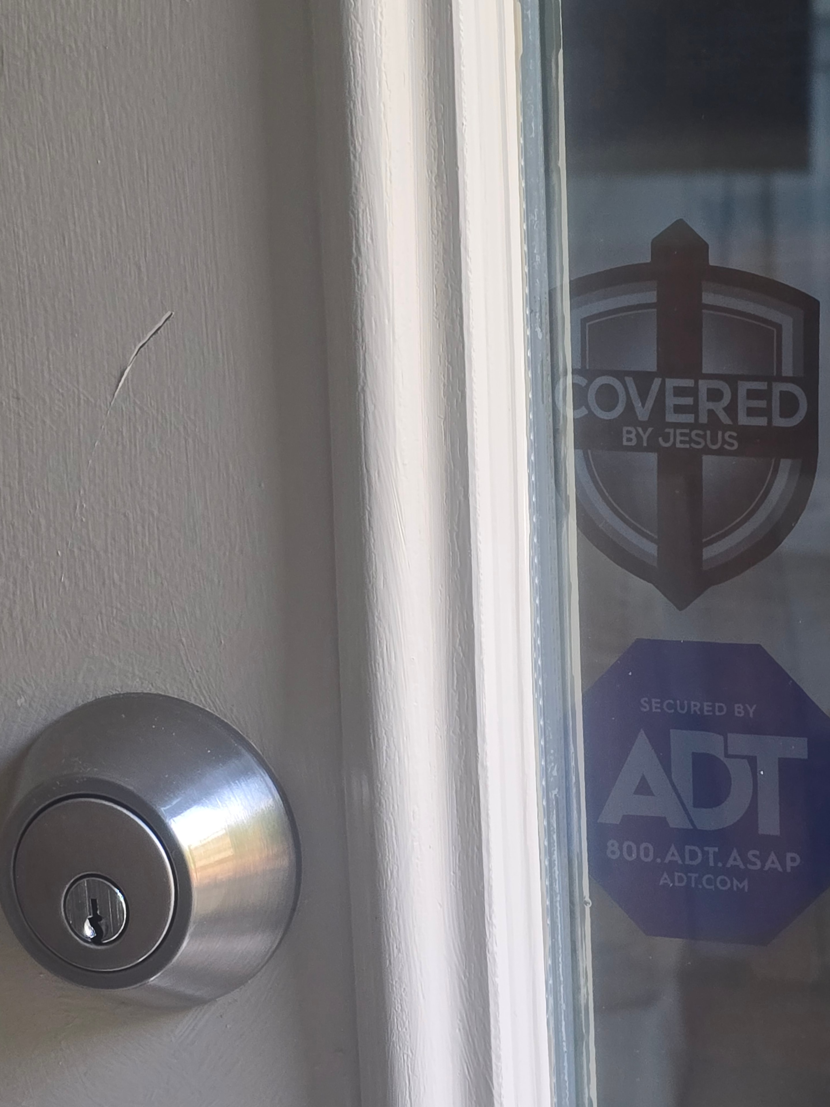 Covered By Jesus sticker placed next to a door deadbolt